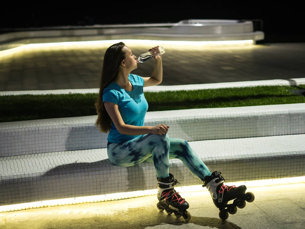 roller skating girl is drinking water from plastic bottle - Photo, Image