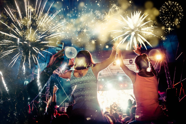 Menschenmenge mit erhobenen Händen beobachtet Feuerwerk - Neujahrskonzept - Foto, Bild