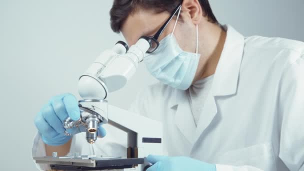 Scientist in uniform looking at microscope - Filmagem, Vídeo