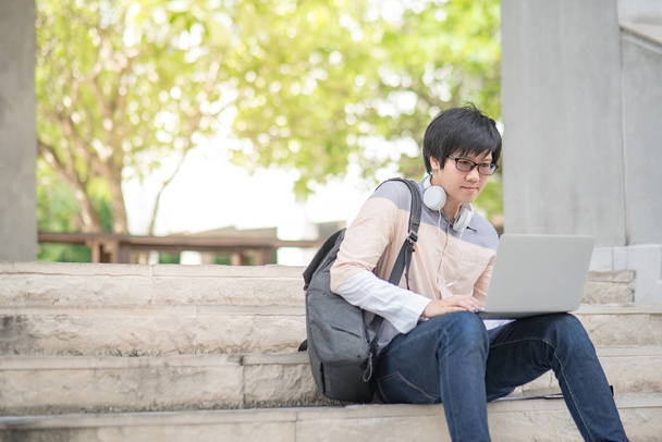 Jovem asiático estudante universitário sentado na escada
 - Foto, Imagem