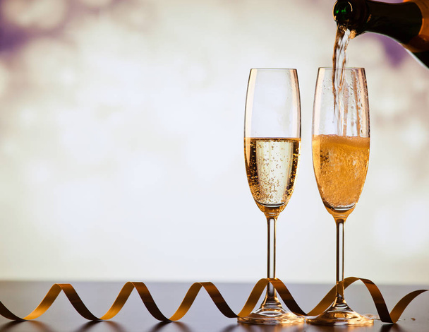 pouring champagne into glasses against holiday lights - Photo, Image