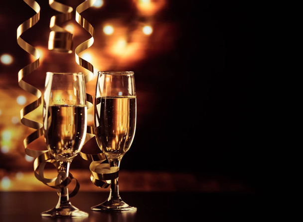two champagne glasses with ribbons against holiday lights and fi - Photo, Image