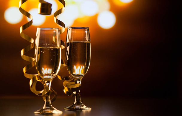 two champagne glasses with ribbons against holiday lights and fi - Photo, Image