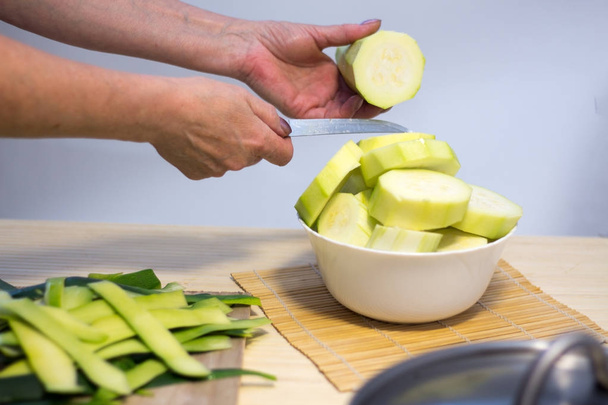 Frau kocht und schneidet frisches Gemüse auf rustikaler Küchenarbeitsplatte, gesundes Ernährungskonzept, flache Lage - Foto, Bild