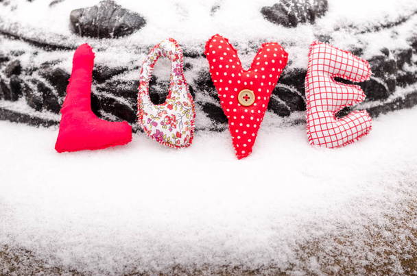 Handmade word love of snow is made of textiles. Bright colored Christmas decor on the snow. Valentine's Day. Sewing toys. - Photo, Image