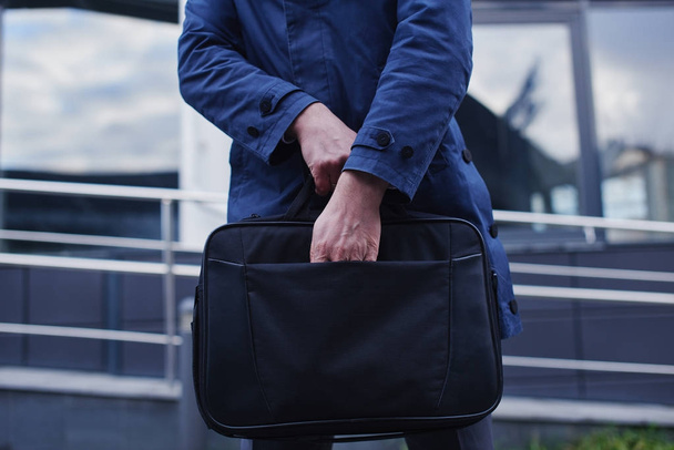 businessman putting hand in pocket of briefcase, close-up  - 写真・画像