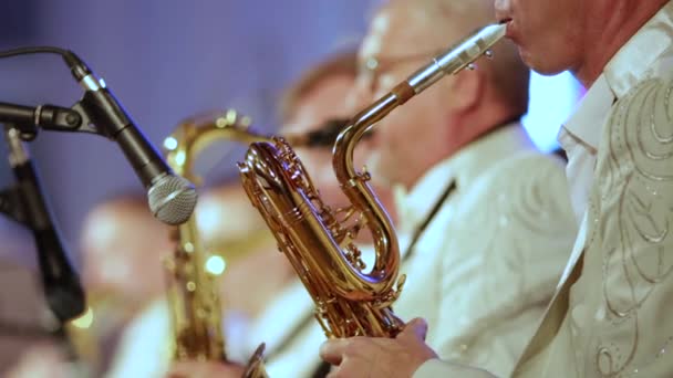 Nahaufnahme. die Musiker der Blaskapelle in weißer Kleidung spielen Saxophone. - Filmmaterial, Video