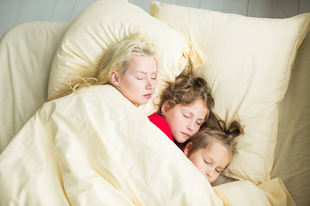 une famille repose sous une couverture au lit
 - Photo, image