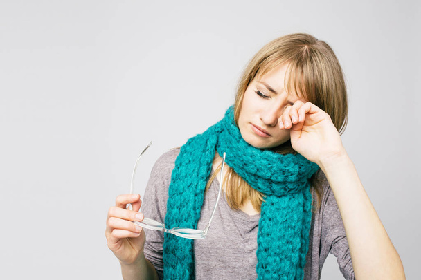 красива молода жінка в в'язаному шарфі страждає від головного болю, що стоїть на сірій стіні
  - Фото, зображення