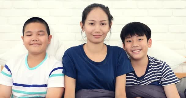 Gelukkige Aziatische-familie broer zus en vriend met je gezicht op het bed thuis. - Video