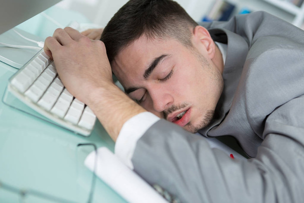 young business man tired and sleeping on his desk - Foto, Bild