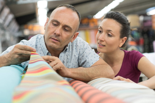 couple choosing a carpet holding up a sample swatch - Foto, afbeelding