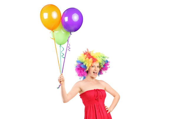 Girl with a wig holding a bunch of balloons - Foto, Bild