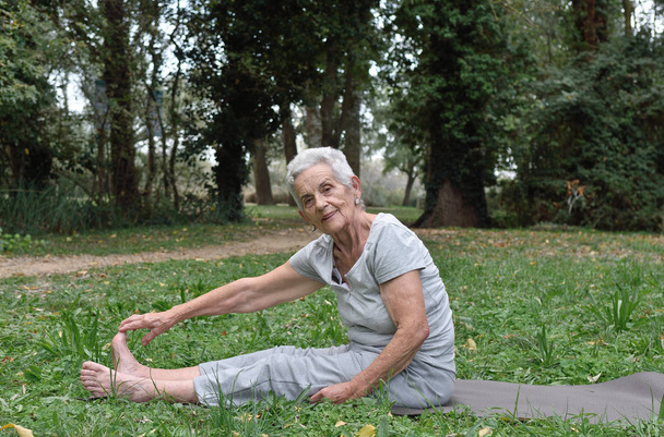 an older woman doing yoga outdoors - Photo, Image