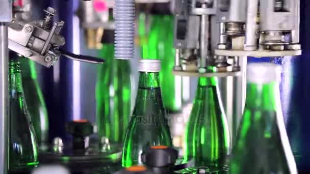 Cobrindo automaticamente garrafas com tampas em planta de água. Garrafas de vidro verde na linha de transporte automático
. - Filmagem, Vídeo