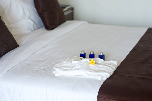 bathroom amenities with bathrobe on bed - Фото, зображення