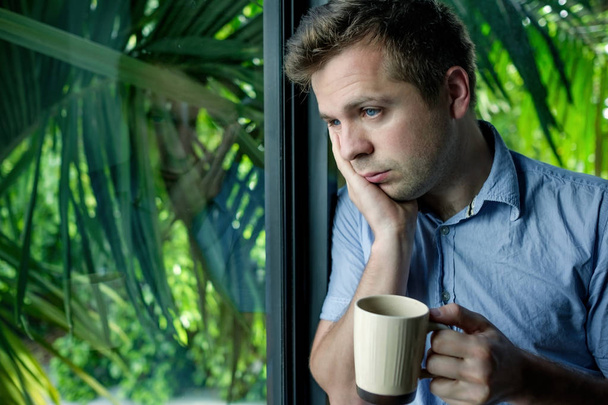 Nahaufnahme Porträt eines Geschäftsmannes, der Kaffee trinkt. Mann blickt durch Fenster und hält Tasse - Foto, Bild