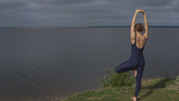 Йога жінка в спортивному одязі проти озера, задній вид - Кадри, відео