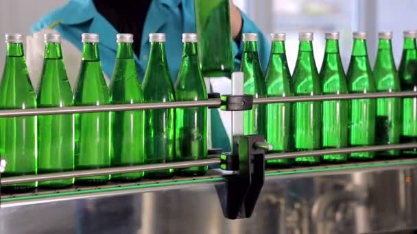 Ein Mitarbeiter der Produktionslinie wischt grüne Glasflaschen für Mineralwasser ab - Filmmaterial, Video