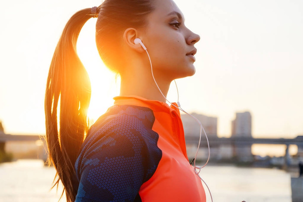 sports fitness girl listening to music in white headphones, in the sun - Foto, Imagem