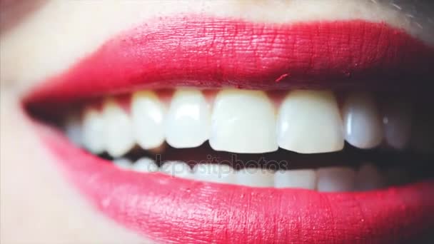 Hermosos labios de mujer con lápiz labial rojo, chica lamiéndose los dientes. Primer plano.
 - Imágenes, Vídeo