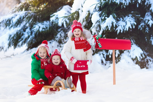 Kinder mit Brief an den Weihnachtsmann am Weihnachtsbriefkasten im Schnee - Foto, Bild