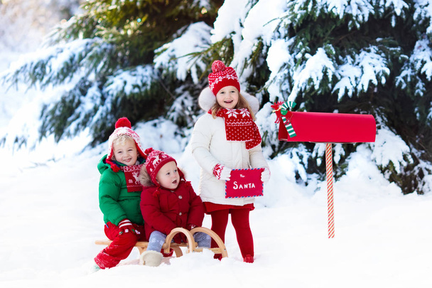 Kinder mit Brief an den Weihnachtsmann am Weihnachtsbriefkasten im Schnee - Foto, Bild