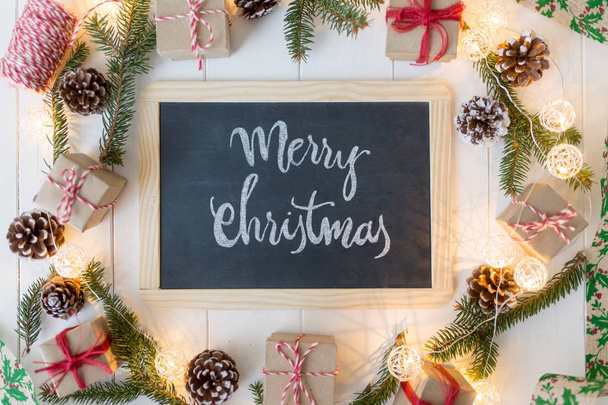 Christmas background with signboard and inscription, spruce, gift box and scroll on wooden boards. - Фото, изображение