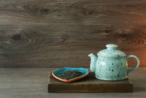 sininen keraaminen teekannu, jossa teetä puupohjalla
 - Valokuva, kuva