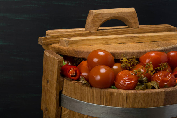 salted tomatoes in a wooden barrel, on a black background - Foto, Imagem