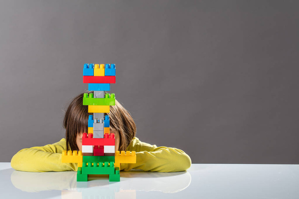 shy little child hiding behind built toy for kid psychology - 写真・画像