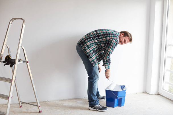 Young man painting a wall on white in a modern home - Фото, зображення