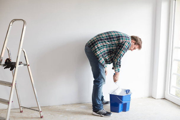 Young man painting a wall on white in a modern home - Фото, зображення