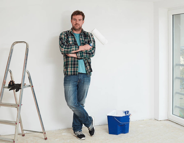 Young man painting a wall on white in a modern home - Valokuva, kuva