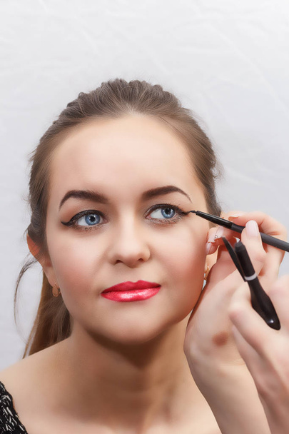 Make-up artist make eye make-up, arrows on eyes, close-up - Foto, afbeelding