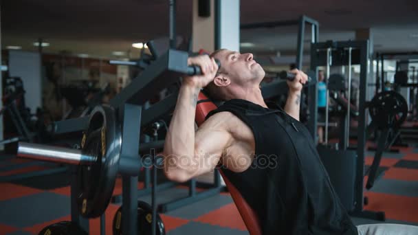 Bodybuilder workout in gym machine - Materiał filmowy, wideo