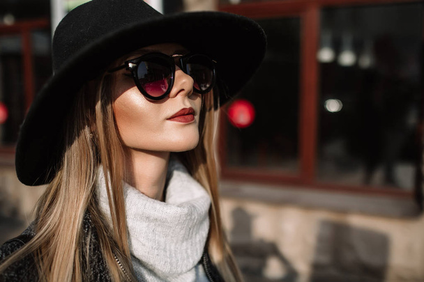 Closeup portrait of a young beautiful fashionable woman wearing sunglasses. A model in a stylish wide-brimmed hat - Foto, Imagem