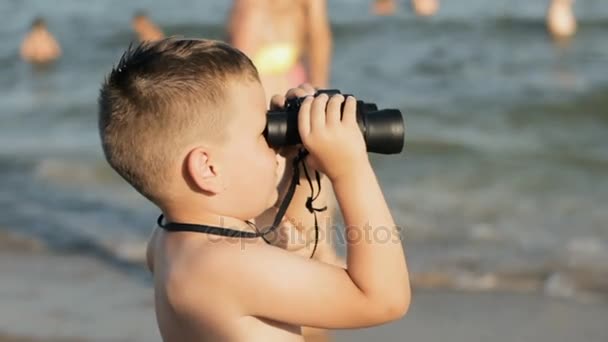 Pequeño chico caucásico mira a través de binoculares y sonrisa
 - Metraje, vídeo