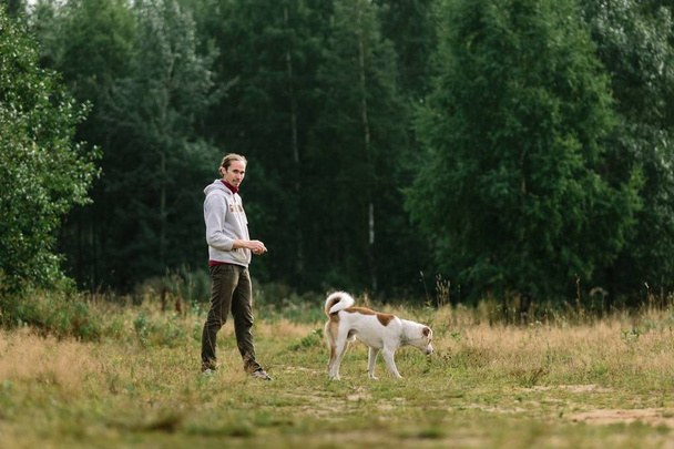 Young man is playing with his dog at nature. - Foto, Bild
