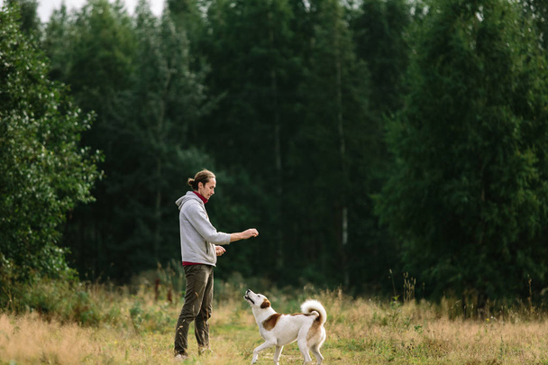 Junger Mann spielt mit seinem Hund in der Natur. - Foto, Bild