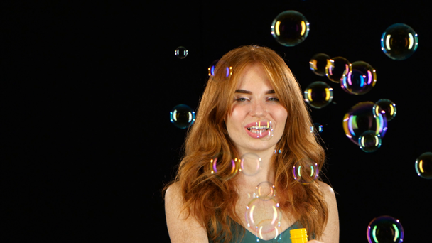 Girl lets the soap bubbles. Black background - Footage, Video