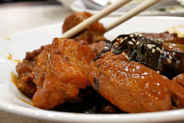 La gente comiendo miel glaseado asado aperitivos de cerdo en la mesa dentro de restaurante chino
 - Foto, imagen