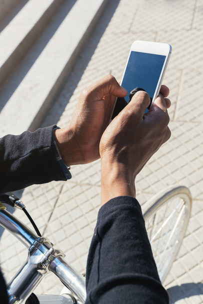 Close up of young man using mobile phone and fixed gear bicycle. - Foto, afbeelding