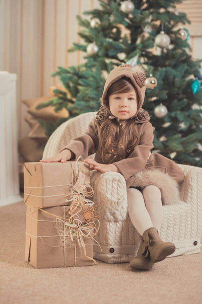 Young brunette dolly lady girl stylish dressed cozy warm winter gray jacket with fur posing sitting standing in studio close to Christmas New Year tree and presents. - Valokuva, kuva