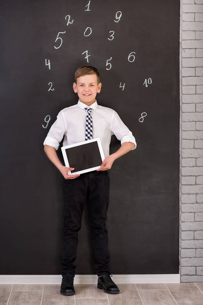 Chłopiec przystojny szkoły w googles biała koszula krawat stojący nieopodal ławce szkolnej z numerami powyżej wokół głowy. - Zdjęcie, obraz