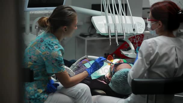 Une dentiste et son infirmière ont scellé la patiente couchée dans le fauteuil d'un cabinet dentaire
. - Séquence, vidéo