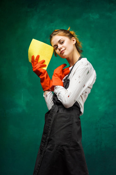 the girl is going to clean. a woman in orange gloves holds a yellow rag in her hands - Photo, image