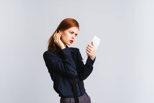 red-haired girl with red lips and in a black shirt looks at herself in the phone, isolated - Foto, immagini