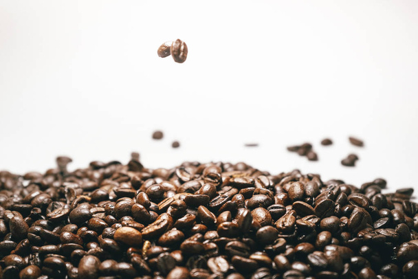a large pile of brown flavored coffee on white background, spilling grains - Valokuva, kuva
