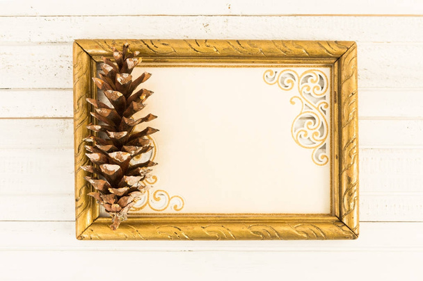 Tarjeta de felicitación en blanco en marco de fotos con cono de pino
 - Foto, imagen